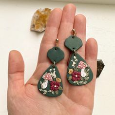 Handmade polymer clay floral mushroom statement earrings. Dark green clay earrings with hand sculpted flowers and greenery. Indulge in the whimsical charm of nature with these darling cottagecore style polymer clay earrings. Each pair is meticulously crafted by hand, ensuring a unique and magical accessory for your everyday adventures. * Nickel Free * Super Lightweight  * Each pair of earrings is handmade and uniquely designed! No two are alike! ** FIND SIMILAR EARRING STYLES HERE: https://www.e Whimsical Green Hand Painted Earrings, Handmade Green Clay Jewelry, Green Polymer Clay Flower Drop Earrings, Nature-inspired Green Dangle Flower Earrings, Handmade Green Clay Earrings, Green Bohemian Polymer Clay Earrings, Bohemian Green Polymer Clay Earrings, Green Hand-painted Polymer Clay Earrings, Hand Painted Green Polymer Clay Earrings