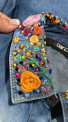 someone is stitching something on their jeans with colorful threads and flowers in the pocket