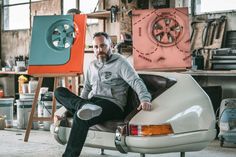 a man sitting on top of a car in a garage