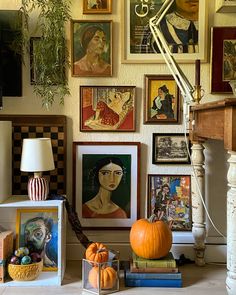 there are many pictures on the wall with pumpkins in front of them and a lamp next to it