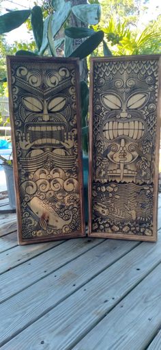 two wooden carvings sitting on top of a wooden table next to a potted plant