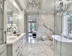 a large bathroom with marble floors and white walls, chandeliers hanging from the ceiling