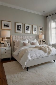 a white bed sitting in a bedroom next to a window with pictures on the wall