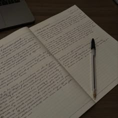 an open notebook with writing on it next to a laptop