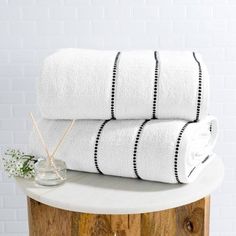 two white towels sitting on top of a wooden table next to a vase with flowers