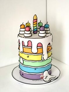 a multi - colored cake with candles on it is sitting on a plate and next to a white wall