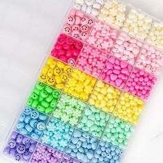 there are many different colors of beads in the plastic box with smiley faces on them