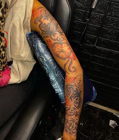 a person sitting in a chair with a tattoo on their leg and arm behind them