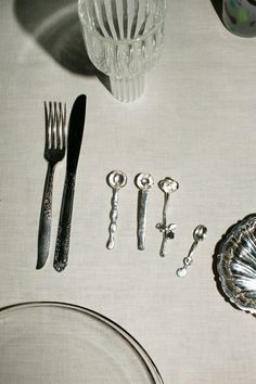 the table is set with silver utensils and glassware, including spoons