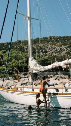 a man standing on top of a boat in the ocean next to a woman and a dog