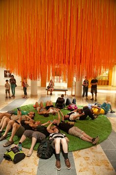 a group of people laying on top of a green rug in a lobby next to orange streamers