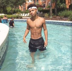 a young man standing in the middle of a swimming pool with his headband on