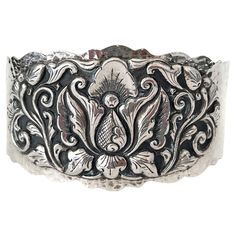 A Djokja silver bracelet crafted with 800 silver typically reflects the rich heritage of Indonesian silversmithing, particularly from Yogyakarta (often referred to as Djokja). The "800" mark indicates that the silver content in the bracelet is 80% pure silver, with the remaining 20% being other metals, usually copper, to enhance durability. The bracelet is an exquisite piece of artisan jewelry featuring a prominently carved lotus flower, a symbol of purity, beauty, and spiritual awakening. The l Elegant Ceremonial Sterling Silver Bracelet With Oxidized Finish, Ornate Engraved Sterling Silver Bracelet, Ceremonial Antique Silver Sterling Silver Bracelet, Traditional Antique Silver Sterling Bracelet For Gift, Traditional Silver Cuff Bracelet For Formal Occasions, Traditional Stamped Cuff Bracelet For Formal Wear, Traditional Stamped Cuff Bracelet For Formal Occasions, Antique Engraved Silver Cuff Bracelet, Ornate Silver Cuff Bracelet With Engraving