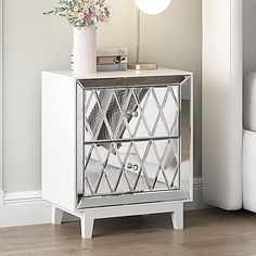 a mirrored cabinet with flowers on top and a lamp in the corner next to it