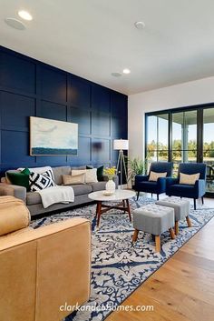 a living room filled with lots of furniture next to a large glass wall window on top of a hard wood floor