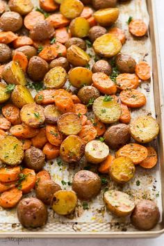 roasted potatoes and carrots on a baking sheet with parsley sprinkled on top