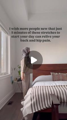 a woman standing next to a bed in a room with a quote on the wall