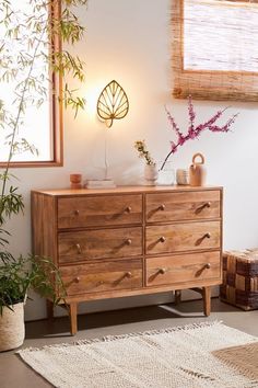 a wooden dresser sitting in a living room next to a plant and potted plants