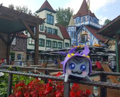 an amusement park with lots of buildings and flowers in the foreground, along with a fence