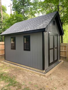 a small gray shed sitting in the middle of a yard