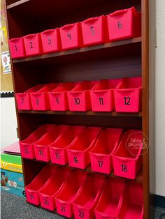 red bins with numbers on them are sitting in front of a bookshelf