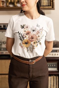 Embrace the beauty of nature with our Autumn Vintage Wildflowers Shirt. This charming Cottagecore-inspired tee features a delicate array of fall botanical florals, with a bee, butterfly, ladybug, and dragonfly throughout. This tshirt delightfully captures the essence of a peaceful meadow in autumn. Perfect for nature lovers, gardeners, and anyone who appreciates the gentle charm of wildflowers. This short-sleeve shirt adds a touch of vintage boho elegance to any wardrobe. PRODUCT FEATURES - Craf Garden Lover Gifts, Flower Shorts, Floral Tee, Garden Lovers, Vintage Boho, Short Sleeve Shirt, Wild Flowers, Gender Neutral, Beauty Book