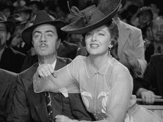 black and white photograph of two people sitting next to each other at a sporting event