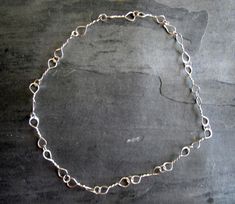 This is a handmade chain made from 18 gauge sterling silver wire. I made long ovals, soldered the ends together, and then gave them a twist in the middle.  They are then connected by a round ring.  The longer links are about 1 1/4" long and are gently hammered to flatten the ends of the loops.   They are all connected by a soldered round ring to make the necklace 23" long.  The clasp is a handmade hook. It was tumble polished for strength and shine.  It can be fastened shorter if you wish. A nice everyday necklace. A perfect gift. Handmade Chain, Sterling Silver Chain Necklace, Twisted Wire, Everyday Necklace, Round Rings, Silver Rings Handmade, Chain Link Necklace, Handmade Sterling Silver, Silver Wire