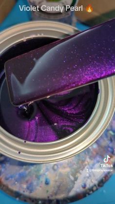 a purple and black object sitting on top of a metal canister filled with liquid