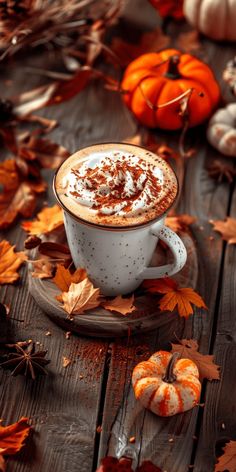 a cappuccino with whipped cream and pumpkins in the background on a wooden table