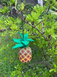 a pineapple ornament hanging from a tree in the yard with green leaves