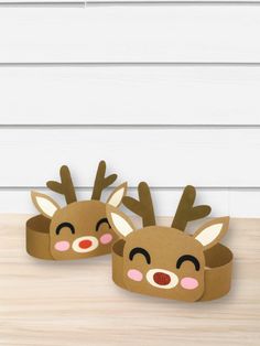 two paper reindeers sitting on top of a wooden table