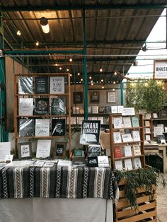 an outdoor market with tables and signs on the wall, hanging from wooden beams above them