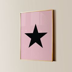 a pink wall with a black star hanging on it's side and a gold frame