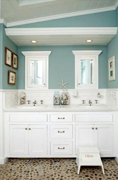 a bathroom with blue walls and white cabinets