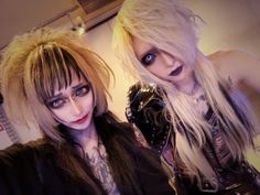 two women dressed up in goth costumes posing for the camera, one with blonde hair and blue eyes