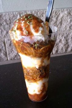 an ice cream sundae with toppings in a tall glass on a black table