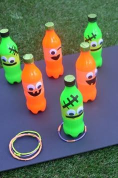 plastic bottles with faces painted on them sitting on top of a mat in the grass