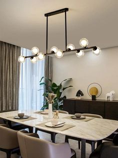 a dining room table and chairs with lights above it