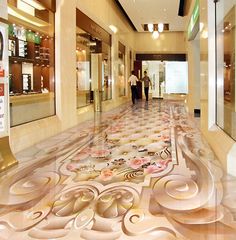 a man walking down a hallway in a building with decorative flooring on the floors