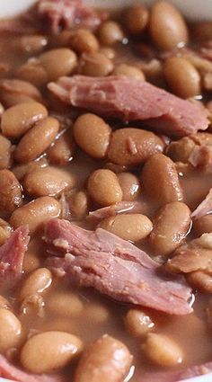 a white bowl filled with beans and ham