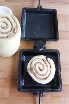 two cinnamon rolls sitting in pans on a table