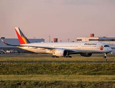 an airplane that is sitting on the tarmac in front of some buildings and grass