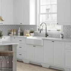 a kitchen with white cabinets and counter tops next to a bar stool in front of a window