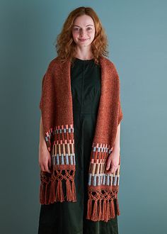 a woman standing in front of a blue wall wearing an orange knitted cardigan