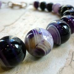 "This is a stunning statement necklace. Purple tone agate stones create a very unique piece. A silver plated bead is placed on the side to give an asymmetric modern look. The necklace combines smaller beads (approx. 1,4 cm) with bigger beads (approx. 1.8 cm) Agate's most noticeable properties overall are balancing yin/yang energy, courage, protection, healing, and calming. Historically it was placed in water for cooking or drinking to dispel sickness. The Metaphysical and Healing Properties Lore Necklace Stacking, Purple Stone Necklace, Cocktail Necklace, Wide Silver Ring, Purple Tone, Big Necklace, Chunky Necklaces, Necklace Purple, Necklace Chunky