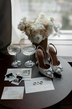 a table topped with two wine glasses and some shoes next to a vase filled with flowers