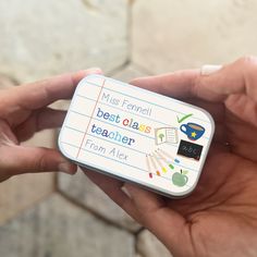 a person holding a small tin with writing on the front and back of it in their hands