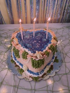 a heart shaped cake sitting on top of a table with lit candles in the middle