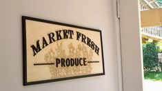 a market fresh produce sign mounted to the side of a white wall next to an open door